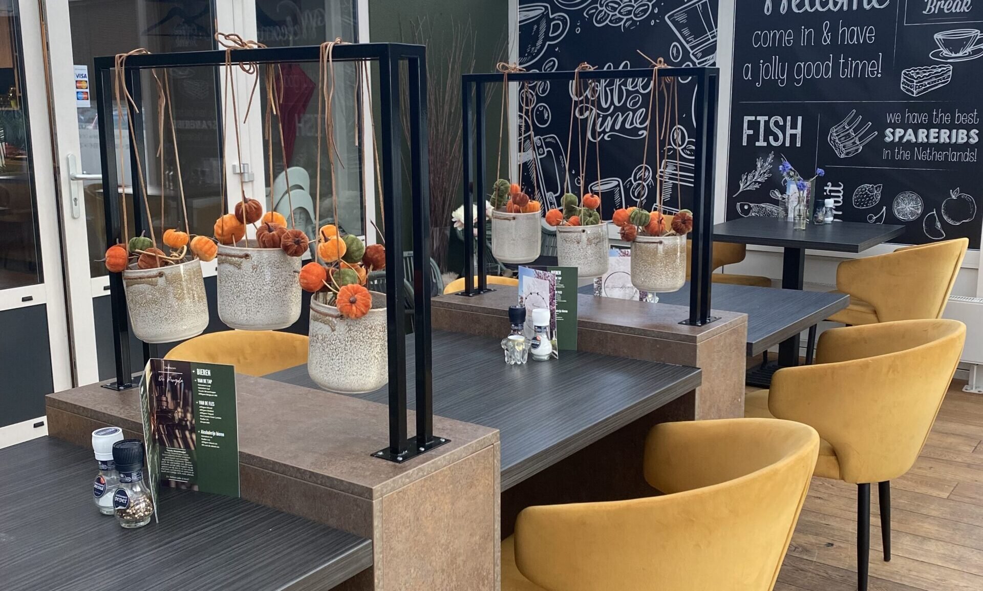 Restaurantinterieur Old Blue met houten tafels en gele fauteuils